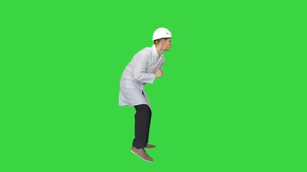 Joven obrero con casco en bata blanca disfruta bailando en una pantalla verde, Chroma Key. — Vídeos de Stock