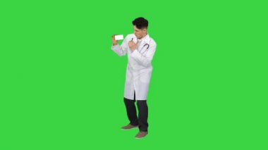 Genç doktor yeni hapları sunuyor ve yeşil ekranda dans ediyor, Chroma Key.