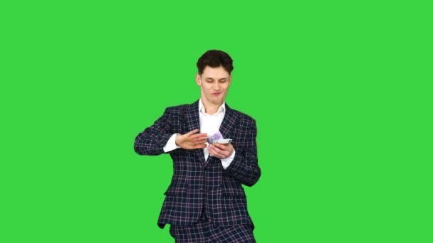 Man in formele pak loopt binnen en gooit geld in de lucht op een groen scherm, Chroma Key. — Stockvideo