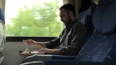 Trende seyahat ederken dijital tablet kullanan yakışıklı adam.
