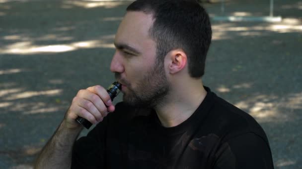 Jeune homme vaporisant une cigarette électronique pour la première fois. être agacé par la fumée. — Video