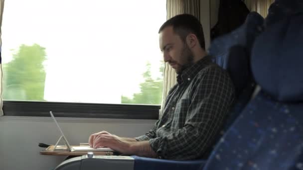 電車の中でタブレットで働いている眠い男が窓のそばに座って. — ストック動画