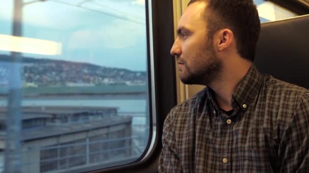 Un uomo serio e sicuro guarda fuori dal finestrino di un treno. — Video Stock