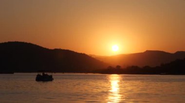 Tekne siluetleri ve tepeleri ile denizde güzel gün batımı.