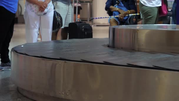 Suitcases on luggage conveyor belt in the baggage claim at airport. People waiting for their luggage. — Stock Video