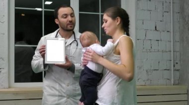 Doktor, anne ve çocuğuna sağlık sonuçlarını tablette gösteriyor. Beyaz Ekran.