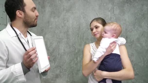 Médico mostrando resultados médicos em um tablet para mãe e bebê. Exposição branca . — Vídeo de Stock