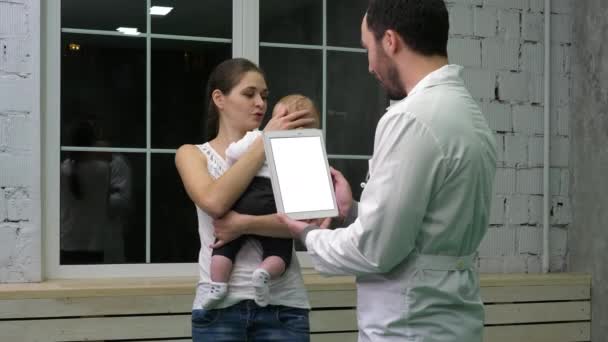 Médico segurando um tablet conversando com a mãe e seu filho. Exposição branca . — Vídeo de Stock