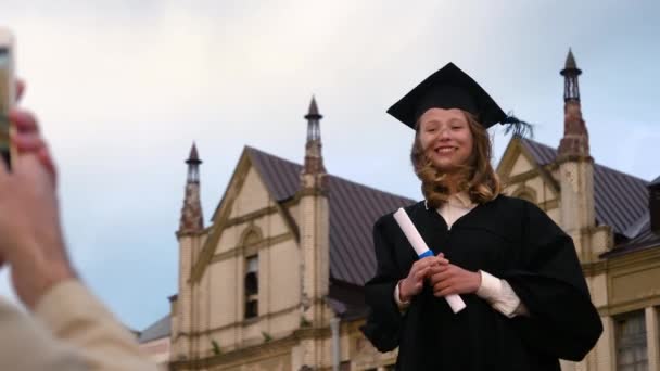 Αποφοίτηση: Κορίτσι φωτογραφίζεται μπροστά από το κολέγιο. — Αρχείο Βίντεο