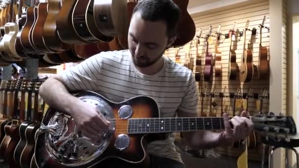 Μόντρεαλ, Κεμπέκ, Καναδάς - 25 Ιουνίου, 2018: Guy playing the guitar in a guitar shop. — Αρχείο Βίντεο