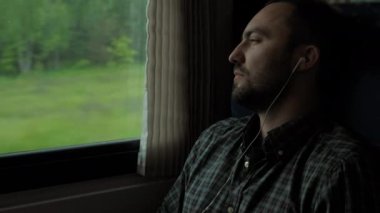 Müzik dinlerken trenle seyahat eden yakışıklı adam..