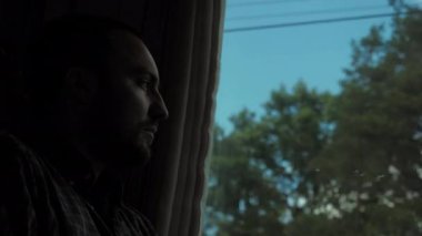 Üzgün genç adam trenin penceresinden bakıyor..