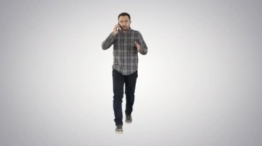 Ciddi bir adam arka planda cep telefonuyla yürüyor ve konuşuyor..