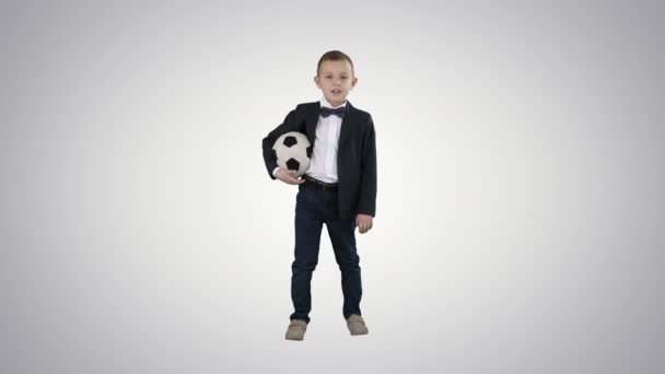 Lycklig ung skol pojke som håller en fotboll på gradient bakgrund. — Stockvideo
