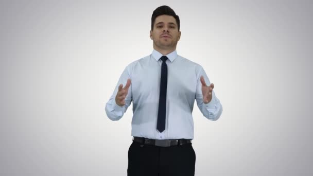 Jonge zakenman lopen in frame en praten met camera presenteren iets op gradiënt achtergrond. — Stockvideo