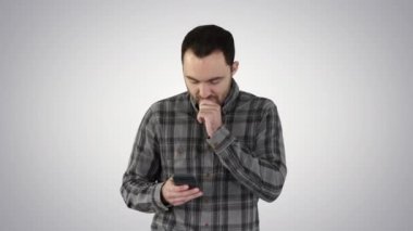 Üzgün genç adam yürüyor ve elini kaldırmadan cep telefonuna bakıyor. Yüzü gradyan arkaplanda..