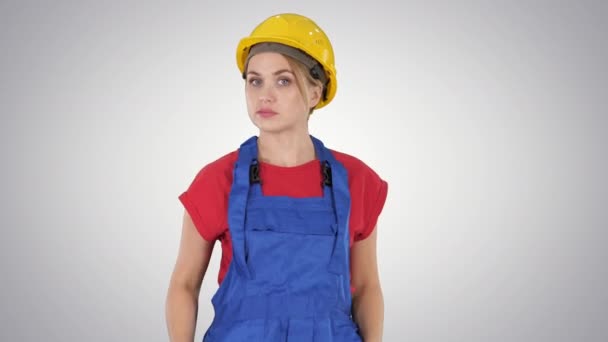 Mujer en traje de construcción hablando con la cámara mientras camina sobre fondo degradado . — Vídeos de Stock