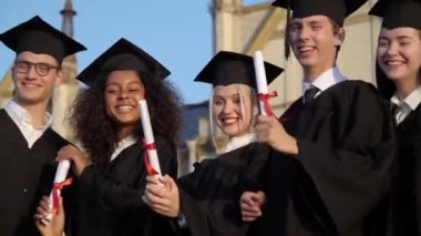 Mutlu genç lisansüstü öğrenciler diplomalarını gösteriyor.