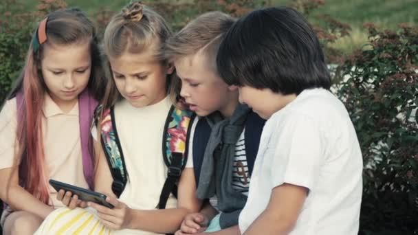 Gruppe von Kindern schaut draußen auf dem Smartphone Zeichentrickfilme. — Stockvideo