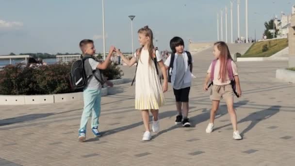 Los niños de la escuela infantil caminando a la escuela con mochilas y dar cinco a cada uno . — Vídeos de Stock