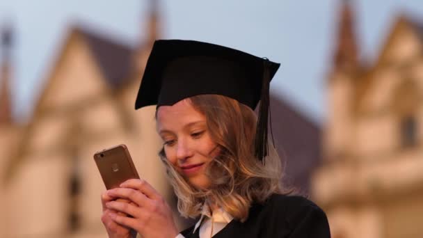 Giovane studente carino laureato sms messaggio sul suo telefono. — Video Stock