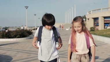 Sırt çantalı okul çocukları yürüyor ve eğleniyorlar..