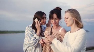 Modaya uygun arkadaşlar akıllı telefonlarını kullanarak birlikte yürüyorlar. Cihaz bağımlılığı.