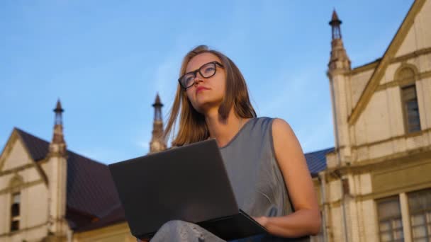 Blondynka pracująca na laptopie podczas siedzenia na świeżym powietrzu. — Wideo stockowe