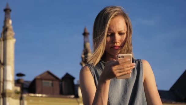 Junge hübsche Kaukasierin sitzt im Park und benutzt Smartphone. — Stockvideo