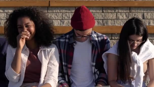 Beristirahat dengan teman-teman. Lima teman sekelas tersenyum duduk bersama setelah kelas di luar universitas . — Stok Video