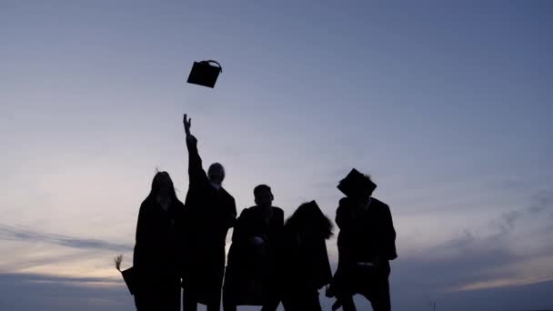 졸업식을 기념하는 다양 한 국제 학생들의 실루엣 이 공중에서 모자를 던지는 모습. — 비디오