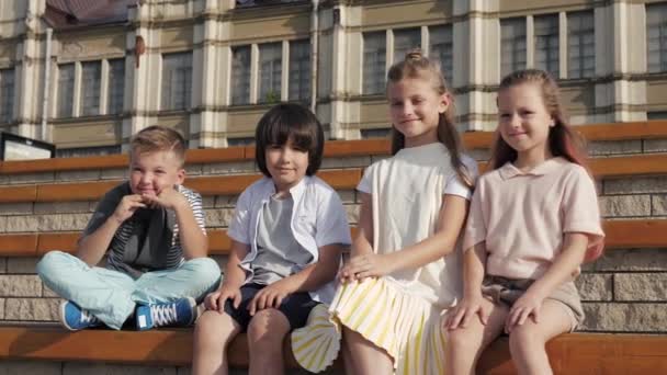 Grupo de crianças pré-escolares sorrindo para a câmera sentados juntos . — Vídeo de Stock