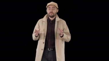 Trençkotlu yakışıklı adam Alpha Channel 'da yürüyor ve kamerayla konuşuyor.