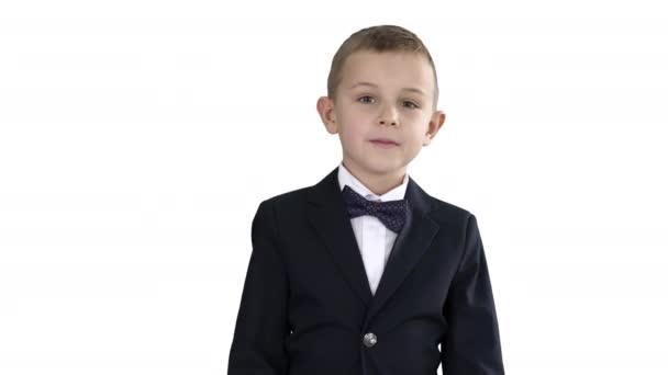 Kleine jongen in een kostuum met een strikje lopen op witte achtergrond. — Stockvideo