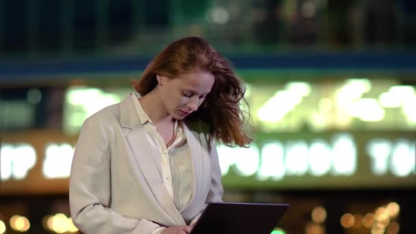 Jonge vrouw met laptop werken in de avond buiten. — Stockvideo