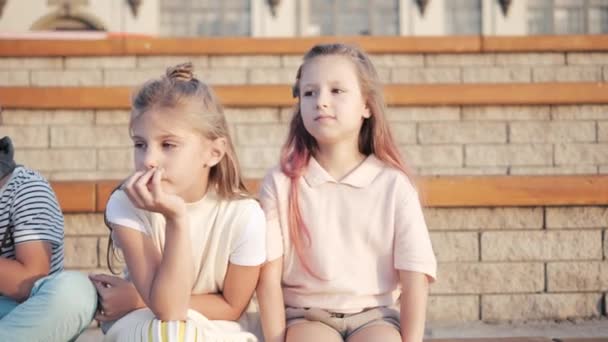 Lindos niños y niñas sentados en un parque. — Vídeo de stock