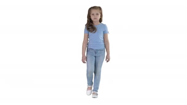 Маленькая девочка в джинсах и синей футболке ходит на белом фоне . — стоковое видео