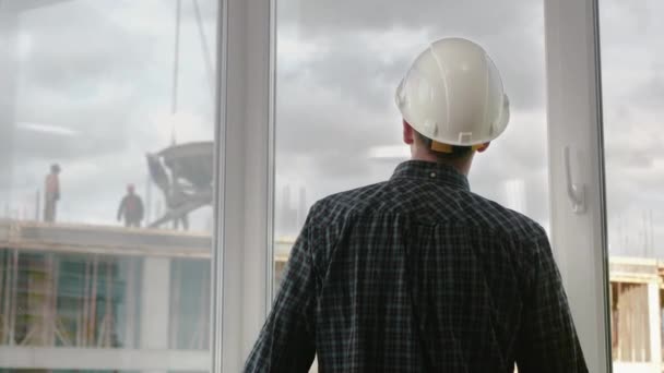 Un ouvrier de la construction regardant les travaux de construction. — Video