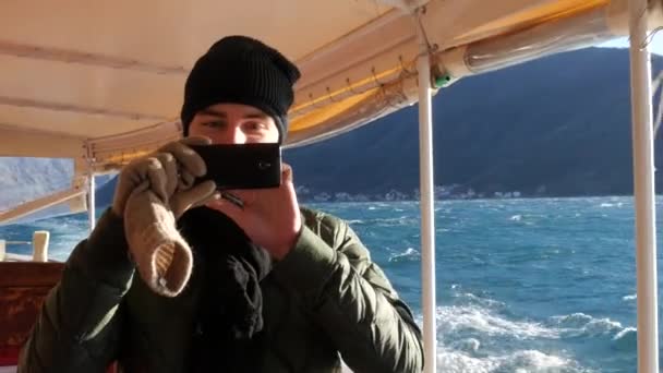 Turista con teléfono móvil en barco en el mar tomando fotos . — Vídeos de Stock