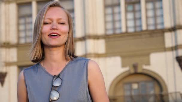 Attraente giovane donna bionda affronta la fotocamera e parla sorridente . — Video Stock