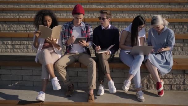 Estudiantes universitarios alegres estudian juntos después de clases. — Vídeos de Stock