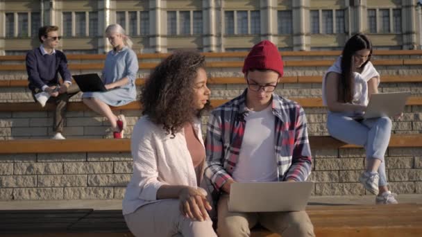 대학 밖에서 노트북으로 프로젝트를 하는 학생들. — 비디오