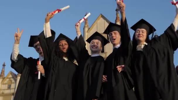 Happy group of students with arms up at their graduation.