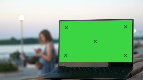 Laptopcomputer op straatbank met groen scherm. Vrouw sms 't. — Stockvideo