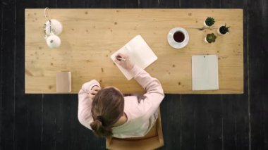 İş yerindeki sıradan bir kadın telefonla konuşuyor, not alıyor, çalıştığı yerde oturuyor.