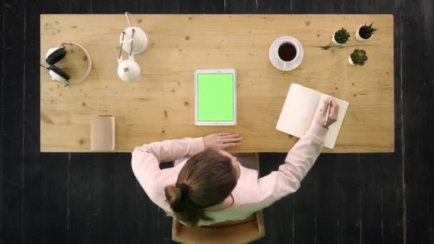 Mujer escribiendo notas de la tableta en el escritorio. Pantalla verde pantalla simulada . — Vídeo de stock