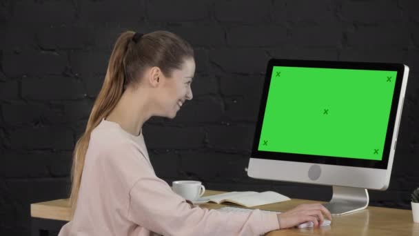 Junge Frau mit blonden Haaren, die am Computer arbeitet und lacht. Green-Screen-Attrappe. — Stockvideo