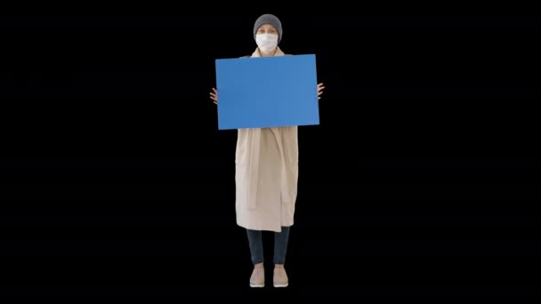 Mujer en ropa de exterior y en máscara médica sosteniendo tablero en blanco, Alpha Channel — Vídeo de stock