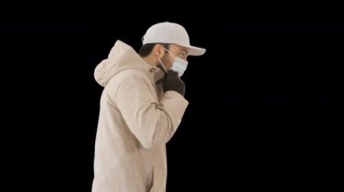 Kış gibi giyinmiş, beyaz bir adam. Tıbbi maske takıyor. Alfa Kanalı.