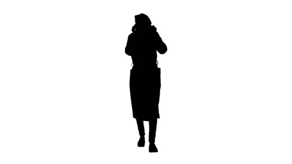 Silhouet Vrouw gekleed in een jas dragen zetten op beschermende gezichtsmasker. — Stockfoto